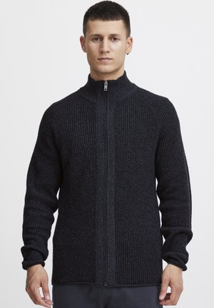 Dark navy zip-up sweater made of textured knit fabric, featuring a high collar and fitted sleeves, with a smooth zipper closure down the front.