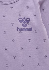 Lavender t-shirt met een gestructureerd patroon van kleine donkerpaarse symbolen en een centraal donkerpaarse "hummel" logo. Zacht katoenmateriaal.