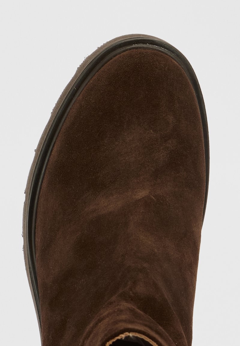Botín de ante marrón hasta el tobillo con punta redonda, suela plana y detalles de costura mínimos. Textura suave, vista en primer plano que muestra variaciones de color sutiles.
