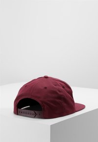 Bordó, pamutból készült sapka, lapos szélekkel. Állítható snapback zárral és hat panelből álló dizájnnal rendelkezik, amelyen szellőző lyukak találhatóak.