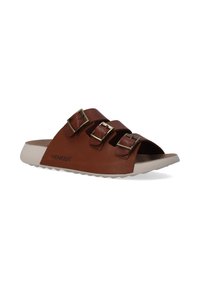Bruine leren slippers met drie verstelbare bandjes en gouden gespen, met een lichtgekleurde, textuurvormige zool en een kurken voetbed.