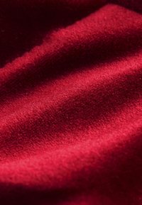 Red fleece fabric with a soft, textured surface, featuring subtle waves and a rich, deep color, creating depth and warmth.