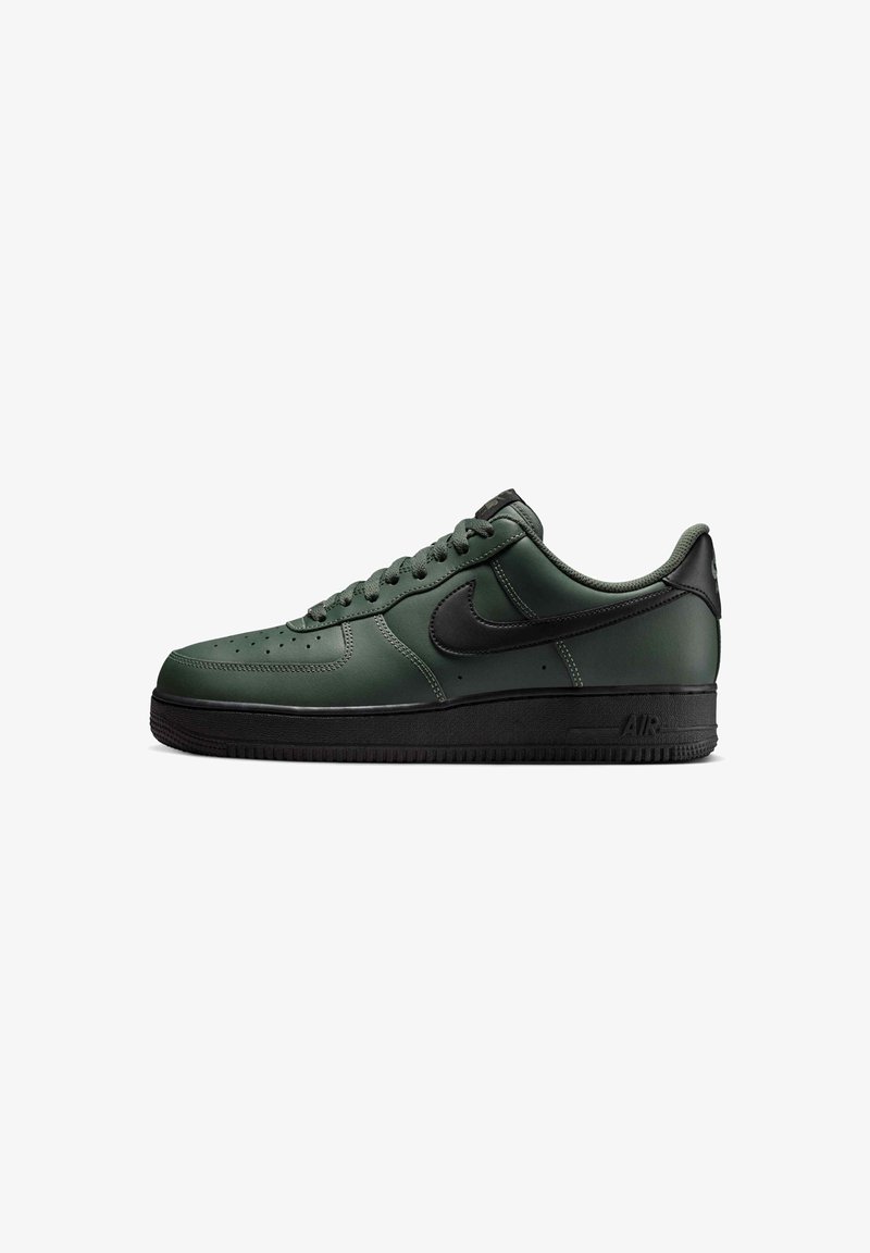 Σκούρο πράσινο sneaker χαμηλού ύψους με μαύρη σόλα, μαύρο λογότυπο Nike, κορδόνια και διάτρητη περιοχή δακτύλων, πλάγια όψη σε λευκό φόντο.