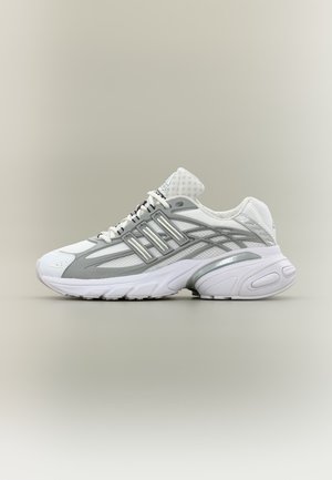 Scarpa da ginnastica bianca e grigia con inserti in mesh e materiali sintetici, chiusura con lacci, suola ammortizzata e sottili strisce del marchio sul fianco.