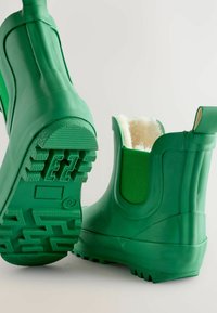 Bottes en caoutchouc vertes hauteur cheville avec une semelle texturée et un doublage doux. Dotées de panneaux élastiques sur les côtés et d'une languette à l'arrière pour un enfilage facile.