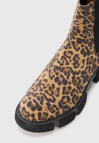 Ankelstøvler med leopardmønster, teksturert semsket skinn på overflaten, svarte elastiske sidepaneler og en kraftig gummisåle for godt grep.