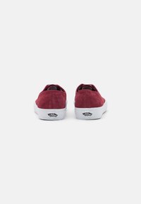 Burgunderfargede semskede sneakers med lav toppdesign, hvit gummisåle og Vans-logo på hælen. Enkle, stilige og med teksturert overflate.