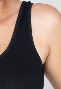 Zwarte tanktop met een ronde halslijn en brede banden, gekenmerkt door een gladde textuur en minimale stikseldetails rond de randen.