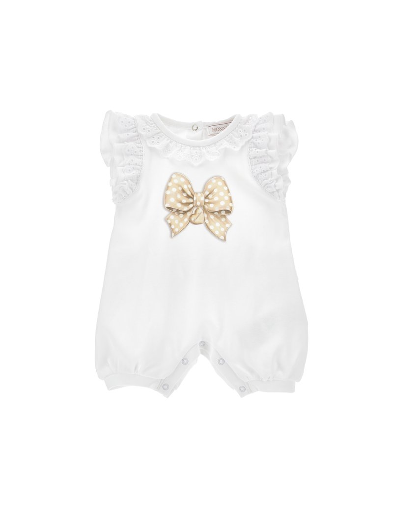 Combinaison blanche pour bébé avec de courtes manches volantes, bordure en dentelle et un grand nœud en polka dots beige sur le devant. Fermetures à pression au bas.