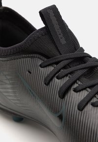 Svart syntetisk fotbollssko med texturerad överdel, central snörning och blå detaljer. Utrustad med dragflik och strömlinjeformad design för bättre prestanda.