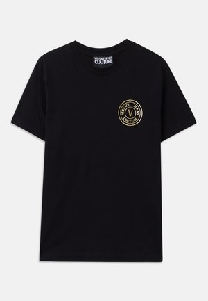 Black cotton t-shirt with a crew neckline and short sleeves. Features a gold circular logo on the left chest. Simple, unembellished design.