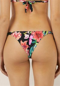 Blommig bikiniunderdel med livliga rosa, orange och gröna mönster på en svart bakgrund. Har en lågriskap och mjuk tygkänsla.