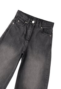 Zwarte denim jeans hebben een klassieke vijf-pocket ontwerp met een knoopsluiting en subtiele vervaging. De textuur is glad met een lichte glans.