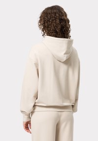 Beige hoodie met een gestructureerde afwerking, geribbelde mouwen en boord, met een relaxte pasvorm en zachte stof.