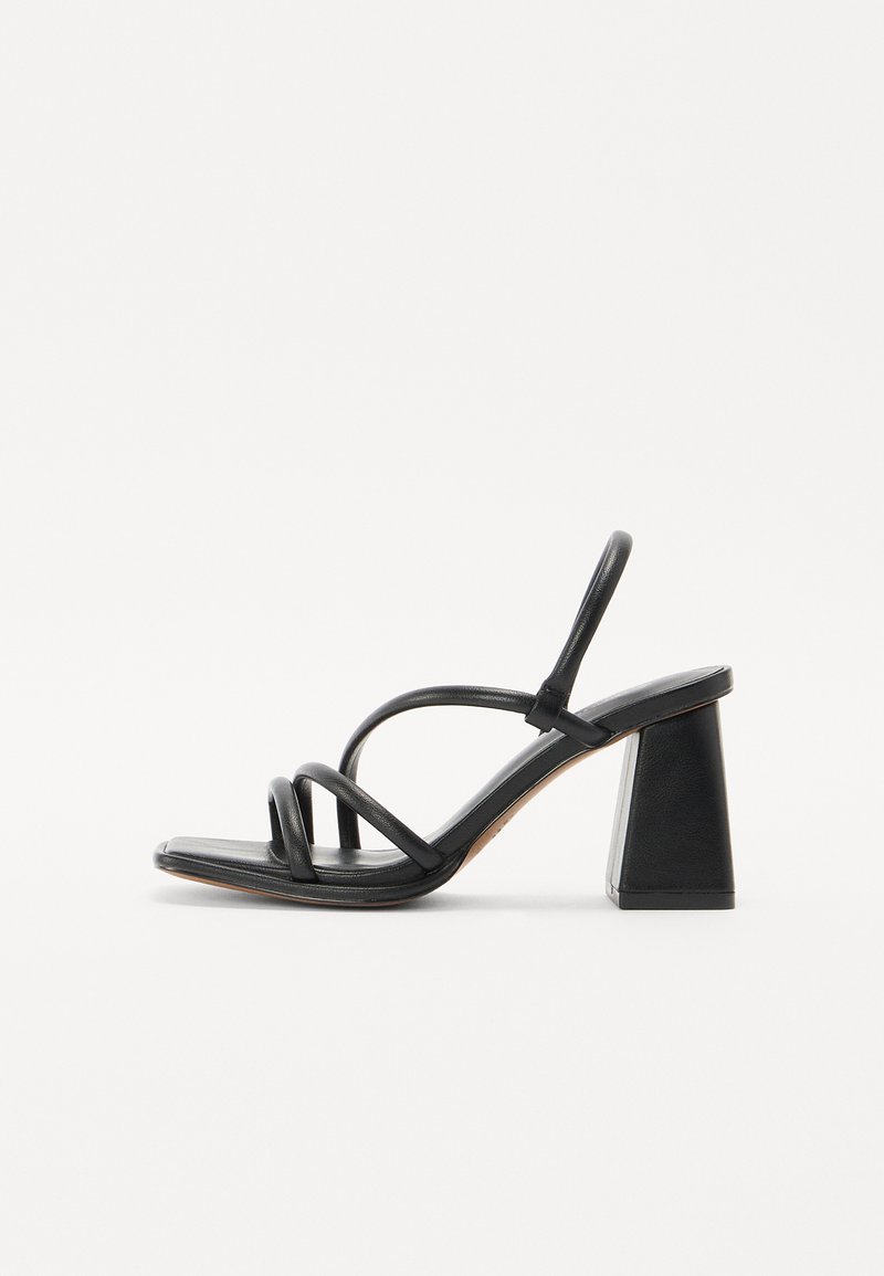 Sandale à talon noir avec un talon carré et épais, présentant plusieurs fines lanières sur le dessus du pied et un design à dos ouvert. Texture en cuir lisse.