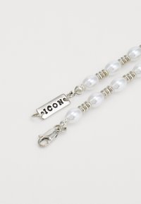 Collier en perles avec accents en argent et étiquette 'ICON', comprenant des perles blanches rondes, de petites perles en argent et un fermoir en métal à griffes de homard.