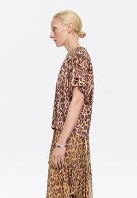 Leopard print short-sleeve top with a relaxed fit, made of lightweight fabric; paired with a matching flowy skirt, also in leopard print.