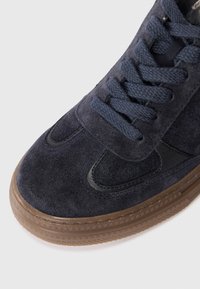 Sneaker in suede blu Navy con superficie texturizzata, suola in gomma, punta rinforzata e lacci abbinati. Presenta un accento in pelle nera liscia.