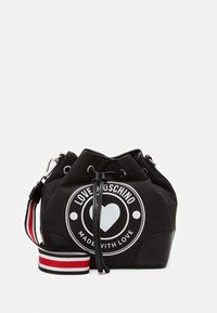 Svart bucket bag med vit logotyp, dragsko-stängning, svarta läderdetaljer och en randig axelrem i rött, vitt och svart.