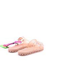 Infradito di plastica rosa chiaro con cinturini trasparenti, fondo testurizzato e fori di ventilazione. Include un’etichetta di imballaggio multicolore.