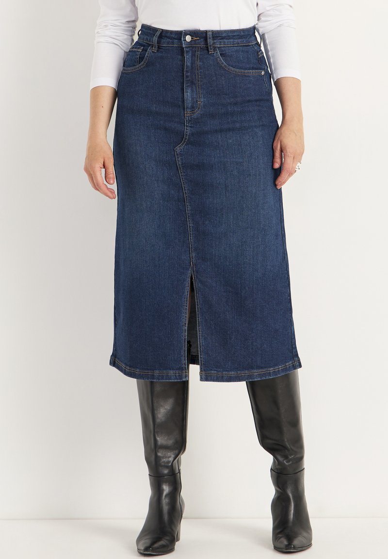 Jupe midi en denim bleu foncé avec une fente avant, cinq poches et des surpiqûres contrastées. Associée à des bottes noires jusqu'aux genoux.