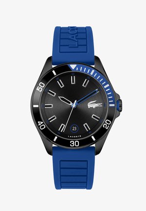 Reloj deportivo con una esfera negra, acentos azules y una correa de silicona azul. Las características incluyen manecillas luminosas, marcadores de hora y una pantalla de fecha a las 23.
