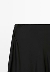 Black satin dress with a smooth, flowing texture. Features a simple design and a discreet zipper at the side for closure.