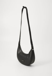 Sac à main en cuir noir avec une forme incurvée, bandoulière réglable, fermeture éclair et un détail en patch à l'avant. Texture lisse, design minimaliste.