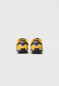 Dzelteni zamša apavi ar jūras zilām akcentiem, ar polsterētu apkaklīti, baltu vidusdaļu un teksturētu melnu ārējo daļu. Logo (Reebok) uz papēža.