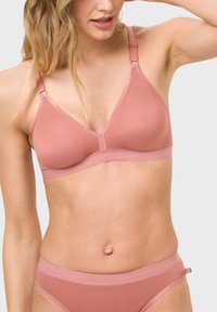 Rosa, dreieckiger Bralette aus glattem Material mit verstellbaren Trägern und minimaler Nahtverarbeitung. Begleitet von einem passenden nahtlosen Hüftbrief.