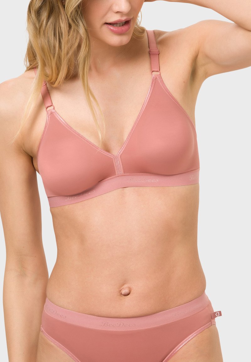 Rosa, dreieckiger Bralette aus glattem Material mit verstellbaren Trägern und minimaler Nahtverarbeitung. Begleitet von einem passenden nahtlosen Hüftbrief.