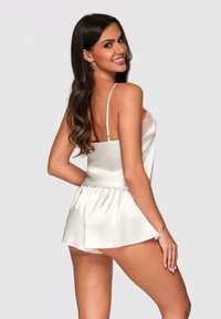 Satin sovset i vitt med en åtsittande cami topp med spetsdetaljer och lösa shorts, som visar upp en mjuk textur och en elegant design.