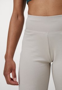 Svetlošedé jogové nohavice vyrobené z elastickej tkaniny, s vysokým pásom a minimálnymi švami pre hladký, elegantný vzhľad.