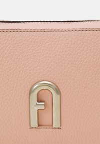 Růžová kožená kabelka s texturovaným povrchem, zlatou kovovou výbavou a výrazným kovovým logem. Hladký povrch s kontrastním prošíváním.