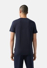 Námorně modré tričko s krátkým rukávem vyrobené z hladkého materiálu. Disponuje kulatým výstřihem a božní etiketou, s jednoduchým a čistým designem.