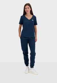 Completo sportivo blu navy composto da una maglietta a maniche corte con scollo a V e pantaloni jogger abbinati, entrambi realizzati in morbido tessuto testurizzato.