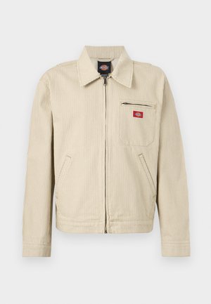 Béžová a bílá pruhovaná bunda na zip s límečkem, dlouhými rukávy, dvěma bočními kapsami a kapsou na zip na hrudi s červenou logovou nášivkou.