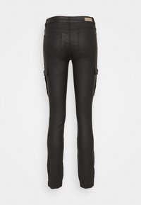 Pantalon noir slim avec des poignets élastiques, deux poches arrière et des poches à rabat sur chaque cuisse, vu de l'arrière.
