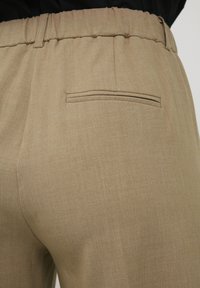 Khaki-Hosen aus strukturiertem Stoff, mit elastischem Bund und einer einzelnen Gesäßtasche mit horizontalem Schlitzdesign.