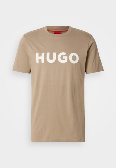Бежова памучна тениска с къси ръкави, с ярък бял текст "HUGO" отпред. Класически дизайн с кръгло деколте, гладка текстура.