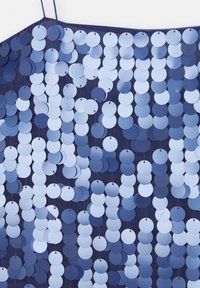 Robe en sequins bleus composée d'une série de sequins circulaires brillants de différentes nuances de bleu, enfilés sur un support sombre.