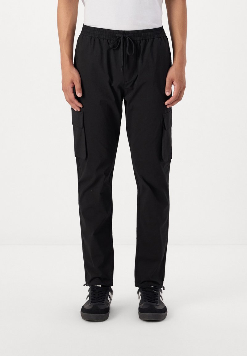 Pantalons cargo noirs avec une taille élastique à cordon de serrage, deux poches latérales et une coupe slim. Tissu texturé avec une finition mate.