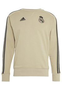 Felpa beige Adidas con logo del Real Madrid e strisce nere che scorrono lungo la lunghezza delle maniche.