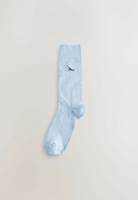 Šviesiai mėlyna medvilninė kojinė su geltonais kraštais ir tamsiai mėlynu aukštakulniu bateliu išsiuvinėtu šalia kulkšnis. Lygi tekstūra, standartinio ilgio.