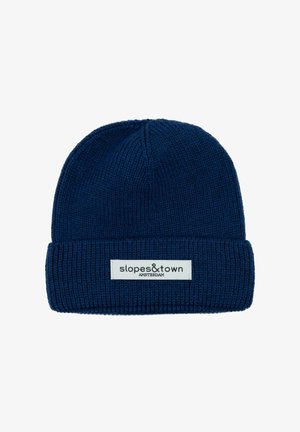 Cappello di lana blu navy con risvolto. Presenta un'etichetta rettangolare con "slopes&town" e "AMSTERDAM" in testo nero su uno sfondo bianco.