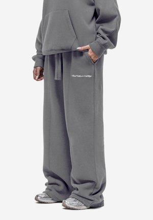Grauer oversized Hoodie mit einer Fronttasche und passenden grauen Sweatpants, die ein gesticktes Logo tragen, aus weichem Baumwollmischmaterial gefertigt.