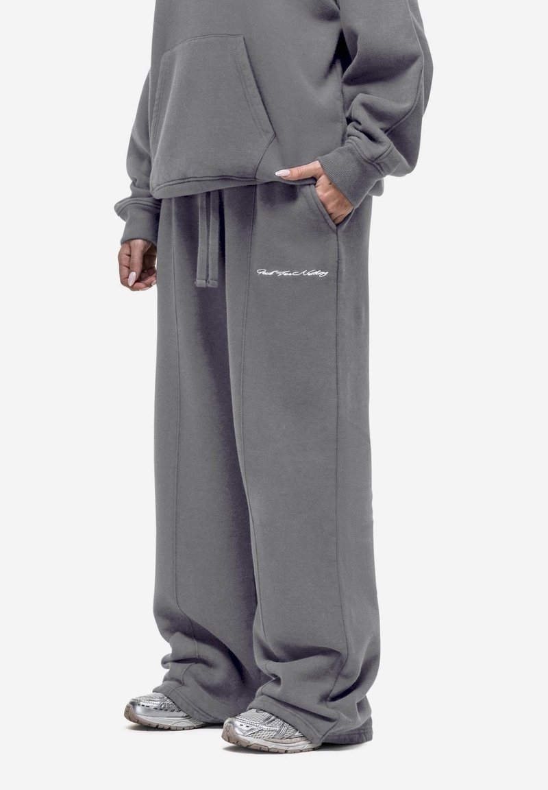 Grijze oversized hoodie met een voorzak en bijpassende grijze joggers met een geborduurd logo, gemaakt van een zacht katoenmix materiaal.