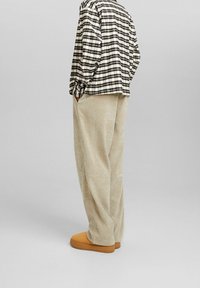 Zwart-wit geruit overhemd met lange mouwen, gecombineerd met beige corduroy broek en lichtbruine instapschoenen. Minimalistisch ontwerp en comfortabele pasvorm.