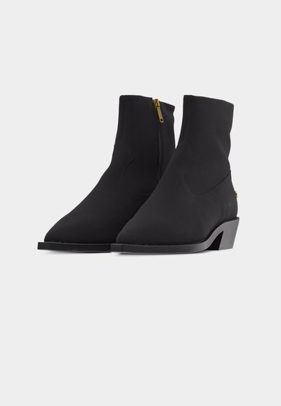 Pair of black ankle boots with side zippers, pointed toes, and low angled heels on a white background.