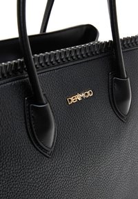 Sac à main en synthétique noir texturé avec des accents lisses, un bord supérieur tressé et une étiquette de logo dorée. Dispose de poignées courtes et robustes.